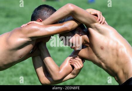 Junge Wrestler, die in einem Arm gehalten werden, kämpfen beim Elmali Turkish Oil Wrestling Festival um die Vorherrschaft. Stockfoto