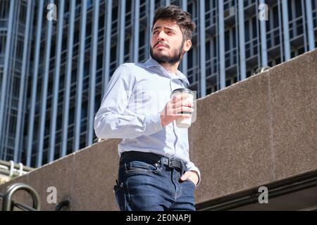 Junger Geschäftsmann mit einer Kaffeetasse in der Hand, der die Treppe hinunter ging. Geschäftsmann in einer städtischen Straße einer Stadt. Stockfoto