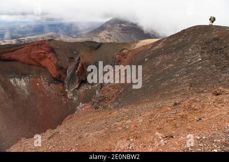 Tangariro, Tongariro Alpine Crossing in der zentralen Nordinsel Neuseelands. Januar 2021. Backpackers stehen am 2. Januar 2021 neben dem Red Crater, dem höchsten Punkt des Tongariro Alpine Crossings in der zentralen Nordinsel Neuseelands. Der Tongariro Alpine Crossing liegt im Tongariro National Park, einem zweifachen Weltkulturerbe, und ist als einer der besten Tageswanderungen Neuseelands bekannt. Kredit: Guo Lei/Xinhua/Alamy Live Nachrichten Stockfoto