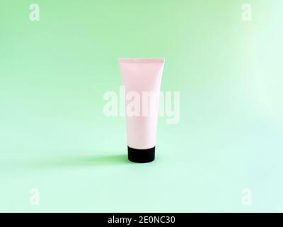 Mock-up von rosa Squeeze Flasche Plastikschlauch mit schwarzer Kappe auf grünem Hintergrund. Flasche für Branding und Etikett. Natürliche Bio-Spa-Kosmetik-Konzept. Stockfoto