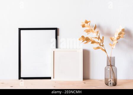 Getrocknete Blumen und ein Fotodramen rammen gegen eine helle Wand hinein Ein minimalistischer Stil Stockfoto