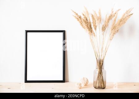 Getrocknete Blumen und ein photoframe gegen eine helle Wand Ein minimalistischer Stil Stockfoto