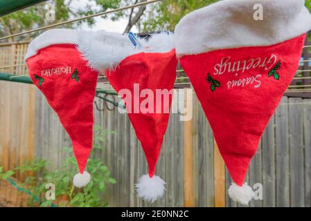 Nach Weihnachten und nach der Weihnachtszeit war Clause in Australien Die Santa Hüte bekommen eine Wäsche und werden hingehängt In der Sonne auf der Wäscheleine trocknen Stockfoto