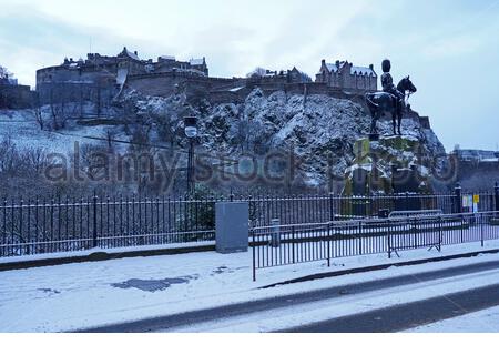 Edinburgh, Schottland, Großbritannien. Januar 2021. Schnee fällt kurz vor Sonnenaufgang im Stadtzentrum. Edinburgh Castle mit einem Staubwedel von Schnee. Kredit: Craig Brown/Alamy Live Nachrichten Stockfoto