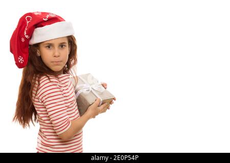 Kleine schöne Mädchen in Weihnachtsmann Hut hält ihr Geschenk Gierig Blick auf die Kamera aggressiv isoliert Copyspace egoistischen Kindern Kinderschmil Stockfoto