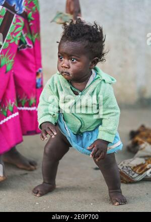 Ranohira, Madagaskar - 29. April 2019: Unbekannt kleiner madagassischer Junge, barfuß, kaum stehend, Mutter steht in der Nähe. Die Menschen in Madagaskar sind arm, aber c Stockfoto