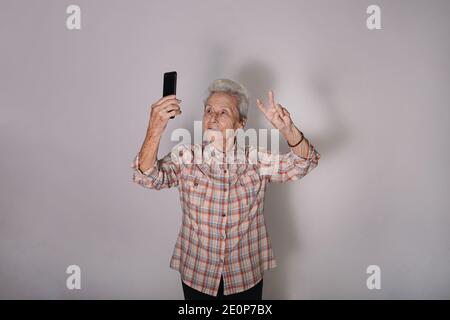 Alte Frau nimmt ein Selfie mit dem Symbol des Friedens. Stockfoto