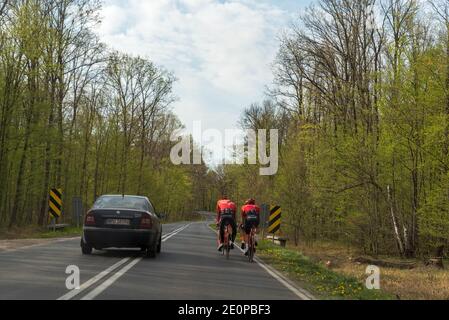 Warschau, Polen - 24. April 2020: Frühjahrstraining. Eine Gruppe von Radfahrern trainiert auf einer öffentlichen Straße neben vorbeifahrenden Autos Stockfoto