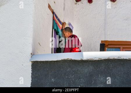 Tibetischer buddhistischer Mönch mit traditioneller roter Robe, der den Tempel im Kloster Thiksey in Leh-Ladakh, Kaschmir betritt Stockfoto