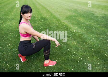 Mädchen mit fit Körper auf grünem Hintergrund mit Copy Space. Weibliche Modell in Sportbekleidung Sport im Freien. Stockfoto