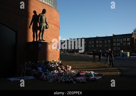 Glasgow, Großbritannien, 2. Januar 2021. Anhänger des Rangers Football Club hinterlassen Blumen und Schals an einer Gedenkstätte (Darstellung Rangers Fußballspieler John Greig) zu den 66 Fans, die ihr Leben in der Ibrox Stadion Katastrophe, die vor 50 Jahren heute am 2. Januar 1971 passiert verloren. Der Jahrestag fällt auf den Tag, an dem Rangers FC spielt ihre Rivalen Celtic FC, zu Hause, in einem Ligaspiel. Foto: Jeremy Sutton-Hibbert/Alamy Live News. Stockfoto