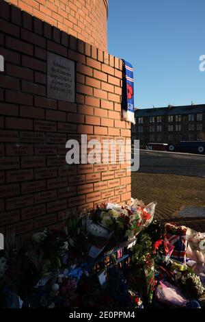 Glasgow, Großbritannien, 2. Januar 2021. Anhänger des Rangers Football Club hinterlassen Blumen und Schals an einer Gedenkstätte (Darstellung Rangers Fußballspieler John Greig) zu den 66 Fans, die ihr Leben in der Ibrox Stadion Katastrophe, die vor 50 Jahren heute am 2. Januar 1971 passiert verloren. Der Jahrestag fällt auf den Tag, an dem Rangers FC spielt ihre Rivalen Celtic FC, zu Hause, in einem Ligaspiel. Foto: Jeremy Sutton-Hibbert/Alamy Live News. Stockfoto