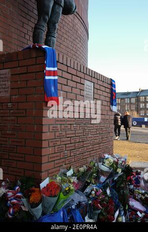 Glasgow, Großbritannien, 2. Januar 2021. Anhänger des Rangers Football Club hinterlassen Blumen und Schals an einer Gedenkstätte (Darstellung Rangers Fußballspieler John Greig) zu den 66 Fans, die ihr Leben in der Ibrox Stadion Katastrophe, die vor 50 Jahren heute am 2. Januar 1971 passiert verloren. Der Jahrestag fällt auf den Tag, an dem Rangers FC spielt ihre Rivalen Celtic FC, zu Hause, in einem Ligaspiel. Foto: Jeremy Sutton-Hibbert/Alamy Live News. Stockfoto