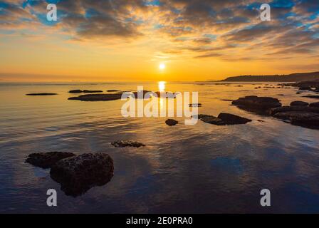 Farbenfroher, heller Sonnenaufgang an der felsigen Küste Stockfoto