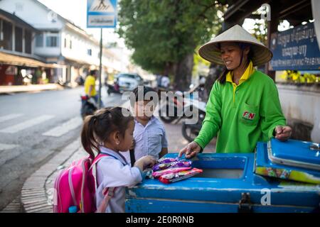 Luang Prabang, Laos - 16. November 2017: Ein unidentifiziertes Schulmädchen, das Eis beim Straßenhändler in Luang Prabang, Laos, kauft. Stockfoto