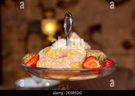 Eine Ausstellung von Wüsten und Donuts mit Erdbeeren auf einem metalltrey Stockfoto
