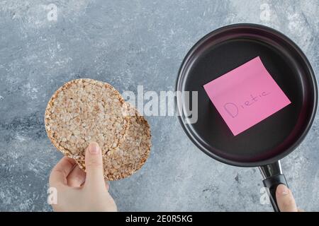 Frau Hand hält eine Pfanne mit aufgeblasen Reisbrot Stockfoto