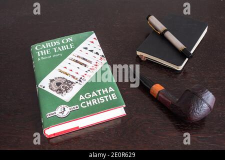 London, England, UK - 2. Januar 2021: Karten auf dem Tisch Buch von Agatha Christie in einer Faksimile-Erstausgabe mit Tabakpfeife, Fountian Pen und Note Stockfoto