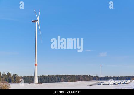 Weitaufnahme eines Windparks und einer schneebedeckten Photovoltaik-Anlage. Stockfoto
