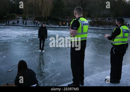 Glasgow, Großbritannien, 2. Januar 2021. Die Leute nutzen das kalte Wetter zum Schlittschuhlaufen und spazieren auf dem gefrorenen Bootsteich im Queen's Park, in der Südseite der Stadt. Die Polizei entfernte schließlich alle aus dem Eis, weil sie sich Sorgen um die Sicherheit gemacht hatte. Foto: Jeremy Sutton-Hibbert/ Alamy Live News Stockfoto