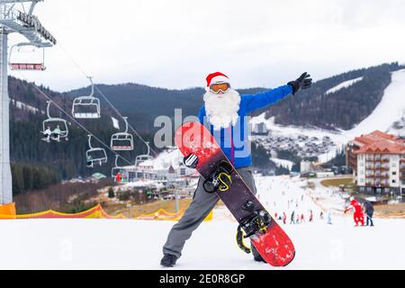 Weihnachtsmann mit Snowboard in den Bergen Stockfoto