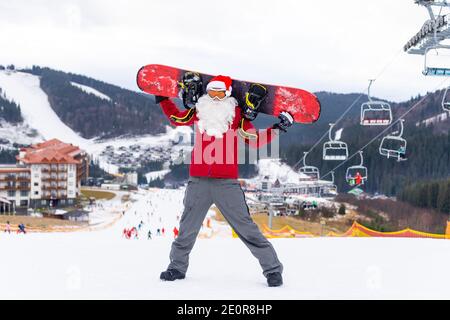Weihnachtsmann mit Snowboard in den Bergen Stockfoto