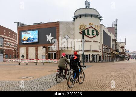 Centro, Oberhausen, NRW, Deutschland. Januar 2021. Zwei Radfahrer, wo Tausende normalerweise spazieren würden, beladen mit Einkaufstaschen. Deutschlands größtes Einkaufszentrum und die umliegenden Restaurants, Cafés und Unterhaltungsangebote wirken düster und menschenleer, die Eingänge sind abgesperrt und geschlossen. Das beliebte Einkaufszentrum mit 125.000 m² Gewerbefläche und der gesamten Außenfläche würde normalerweise mit Käufern auf der Suche nach Schnäppchen in den Januar-Verkäufe hallten. Kredit: Imageplotter/Alamy Live Nachrichten Stockfoto