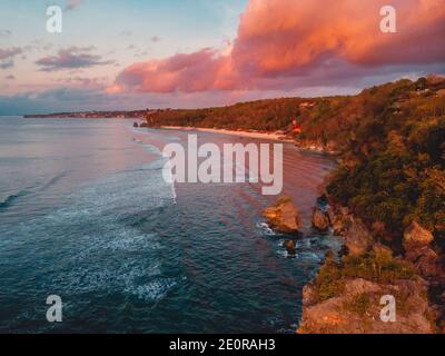 Luftaufnahme der felsigen Küste mit Klippen, Meer und hellen Wolken bei warmem Sonnenuntergang auf Bali Stockfoto