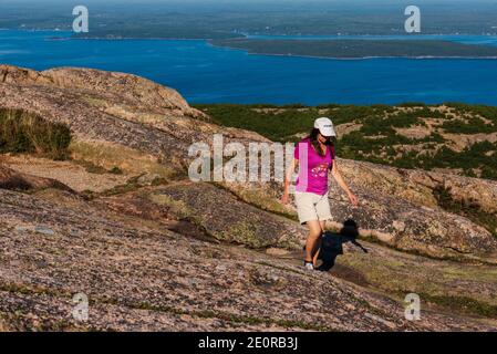 Foto einer Wanderfrau auf dem Caddilac Mountain mit Bar Harbor im Hintergrund. Stockfoto