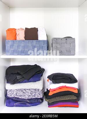 Verschiedene Kleidung im Kleiderschrank mit Papier Notizen. Kleine Raumordnung. Vertikale Lagerung. Rollout-Shirts in Stoffboxen. Stockfoto