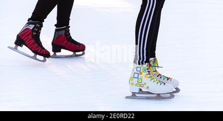 Skater auf der Eisbahn, eine Nahaufnahme der Füße in bunten Frauen-Schlittschuhen. Stockfoto