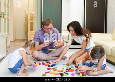 Kleine Mädchen und Junge spielen Bau Set mit Mutter und Vater Stockfoto