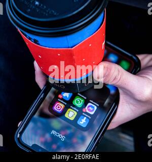 London UK, Januar 02 2021, Young Anonymous man or Male Holding A Smart Mobile Phone and A Cup of Nero Takeaway Coffee Stockfoto