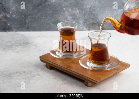 Zwei Glas Tassen Tee mit Teekanne auf einem hölzernen Platine Stockfoto