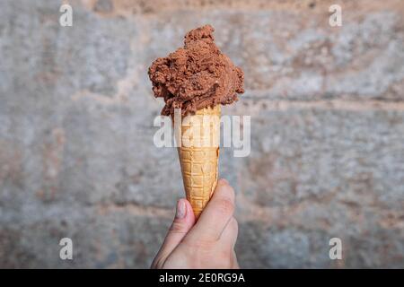 Hand halten Schokolade Eis Kegel. Schokoladeneis in Waffelkegel Stockfoto