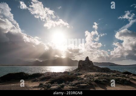 Sonnenstrahlen platzen durch Sturmwolken über Calvi Bay in Die Balagne-Region von Korsika mit der felsigen Mittelmeerküste Und ein alter Genueser Turm Stockfoto