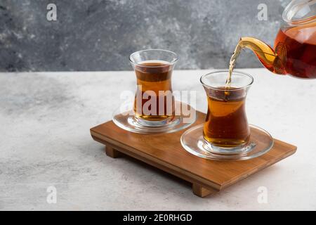 Zwei Glas Tassen Tee mit Teekanne auf einem hölzernen Platine Stockfoto