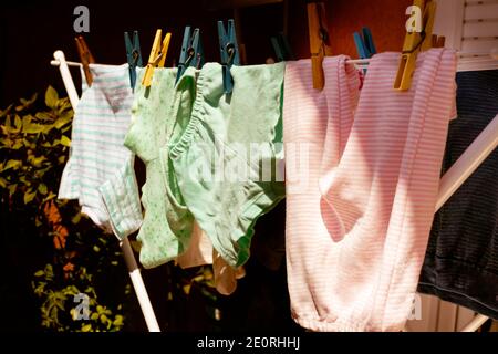 Babykleidung, die an einer Wäscheleine hängt und in der Sonne trocknet. Selektiver Fokus. Stockfoto