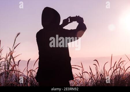 Reisender Mann tragen Pullover nehmen Sie Bilder mit einem Smartphone auf Spitze des Berges Stockfoto