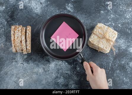 Frau Hand hält eine Pfanne mit aufgeblasen Reisbrot Stockfoto