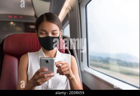 Asiatische Geschäftsfrau mit Mobiltelefon während der Fahrt zur Arbeit Im öffentlichen Verkehr Zug trägt Gesichtsmaske für Corona-Virus Prävention Stockfoto