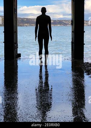 Eine Antony Gormley Gusseisenfigur unter der Promenade des Harbour Arms in Folkestone, Kent, Großbritannien Stockfoto