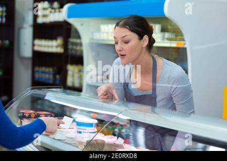 Verkäuferin Verkauf von Käse in Lebensmittelgeschäft zu Mann Stockfoto