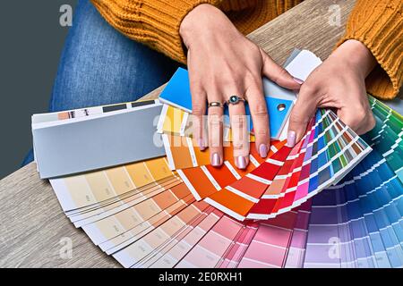 Farbrad zur Auswahl des Farbtons. Hände von weiblichen Innenarchitekten arbeiten mit Palette für die Auswahl von Farben. Kreatives Prozesskonzept. Vergleichen Stockfoto