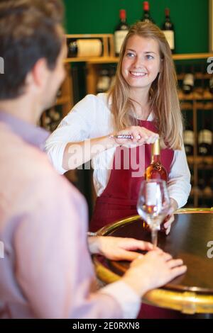 Fröhliche elegante Kellnerin mit einer Flasche Rotwein Stockfoto