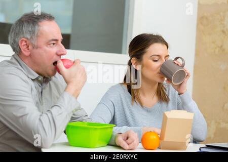 Geschäftskollegen mittleren Alters, die im Büro essen Stockfoto