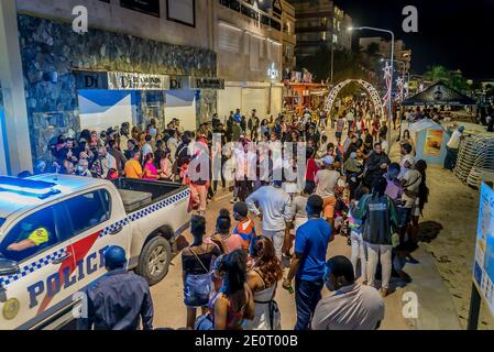 Polizeifahrzeug fährt durch große Menschenmenge und feiert das neue Jahr 2021 auf der Promenade auf der karibischen Insel ST Maarten. Stockfoto