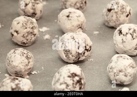 Winter festliches Backen - Schokoladenkekse mit Puderzucker auf Ein Backblech mit Pergament bedeckt Stockfoto