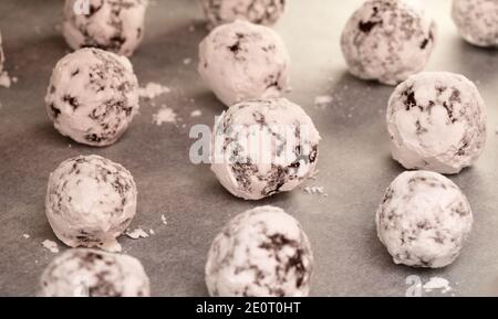 Winter festliches Backen - Schokoladenkekse mit Puderzucker auf Ein Backblech mit Pergament bedeckt Stockfoto