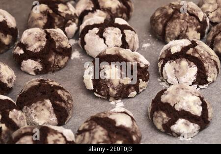 Winter festliches Backen - Schokoladenkekse mit Puderzucker auf Ein Backblech mit Pergament bedeckt Stockfoto